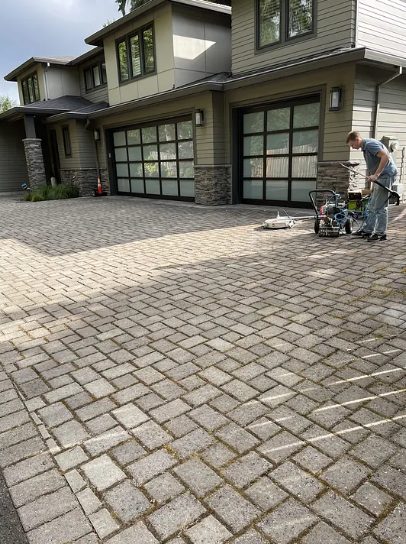 A grimy paver driveway mid-way through pressure washing