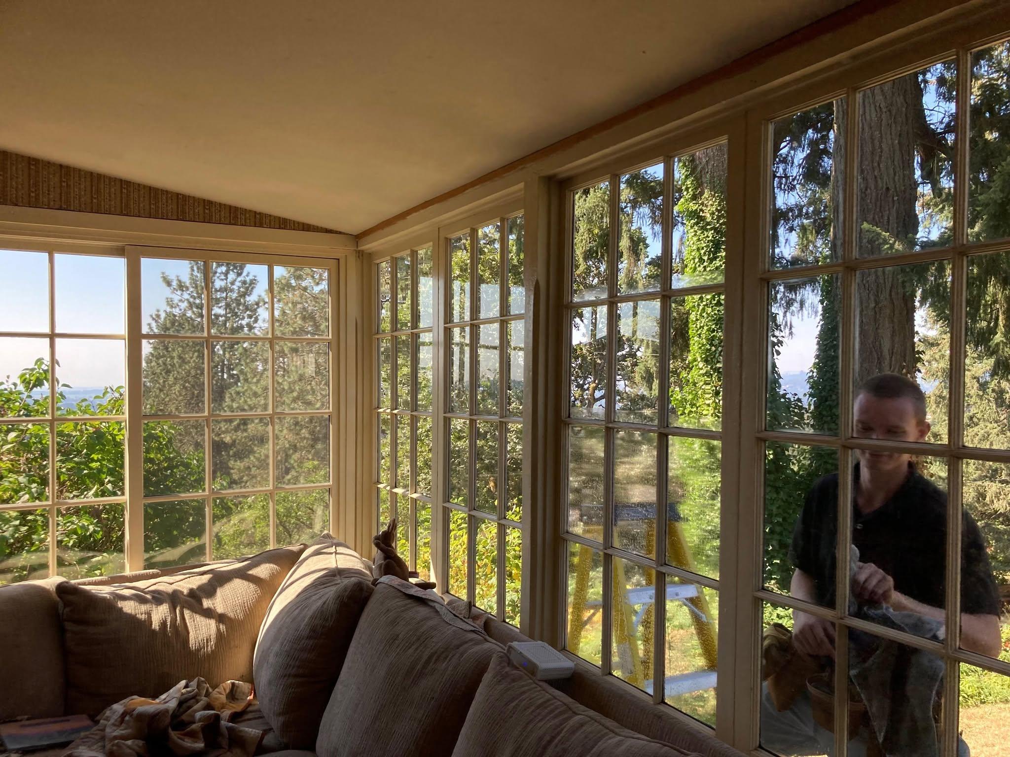 A Valley Boys technician cleaning the windows of a bright sunroom